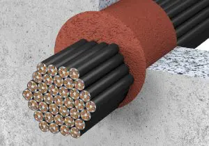 A bundle of insulated wires passes through a circular hole in a concrete wall, sealed with red material as part of UL firestop systems.