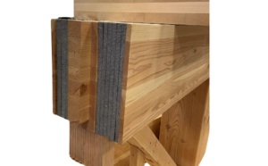 Close-up of interlocking timber beams with grey insulation panels between the wooden layers.