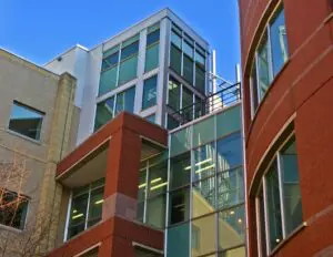 Modern building with large glass windows and red brick and beige exterior against a clear blue sky.