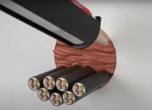 A caulking gun sealing cables passing through a wall with a reddish-brown sealant.