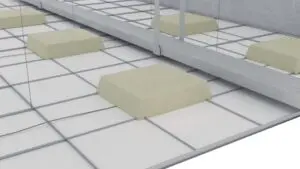 White floor panels with a grid pattern and square beige pads, reflected in a wall mirror.