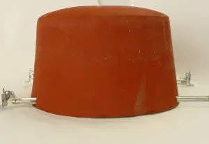 Large red clay pot turned upside down with metal clamps attached, resembling a component used in a 2 hour fire rated ceiling, on a white background.