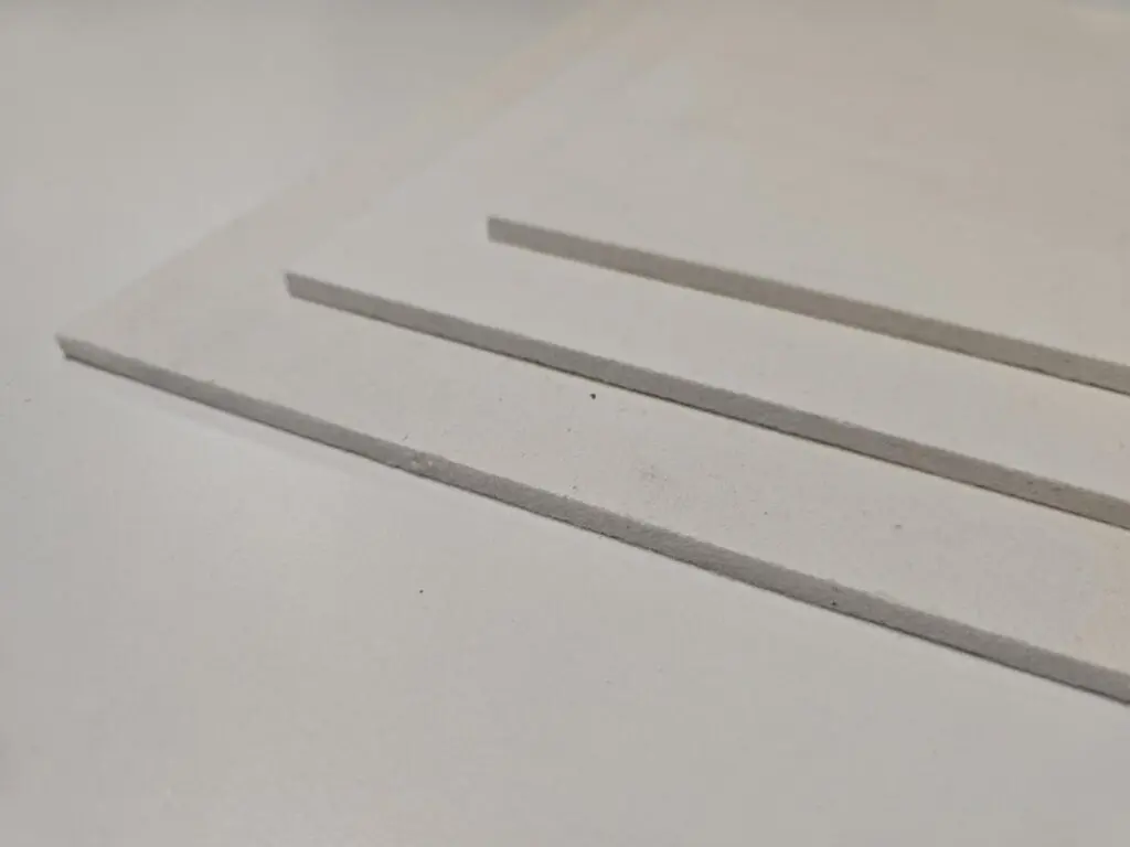 Three white rectangular sheets stacked on a light surface.