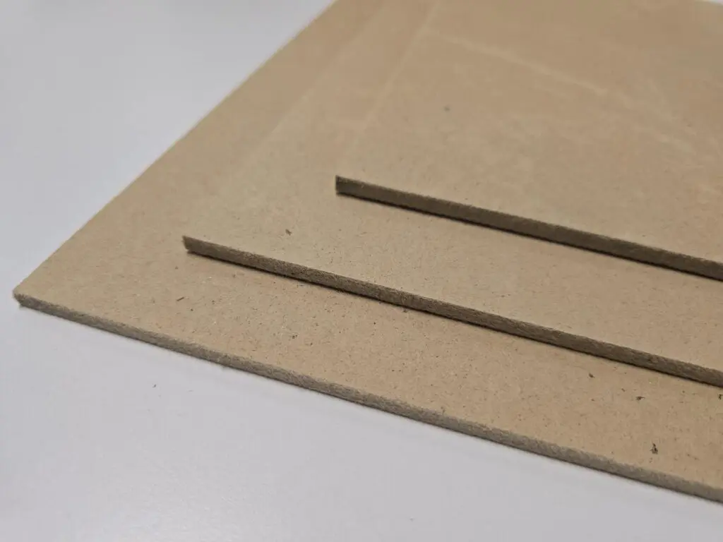 Three MDF sheets stacked on a white surface.