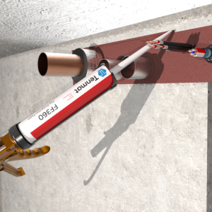 A sealant gun applies red firestop sealant around pipes passing through a concrete wall.