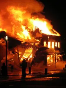 A large building engulfed in flames at night, with smoke rising and intense fire consuming the structure.
