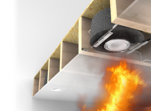 Fire burns below a ceiling, showing insulation and a speaker system installed between joists above the flames.