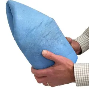 A person holding a large, blue, foam wedge with both hands against a white background.