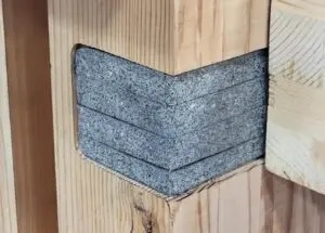 Close-up of a corner joint showing stacked concrete or stone blocks fitted into wood.