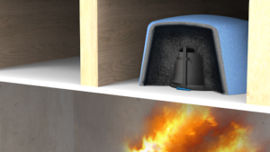 A fire burns below a shelf that holds a protected device inside a foam or insulated cover.