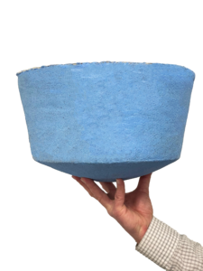 A hand holds a large, blue, textured bowl against a white background.