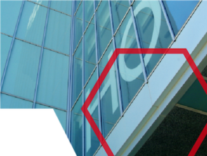 Glass building facade with large white letters and a red hexagonal outline in the foreground.