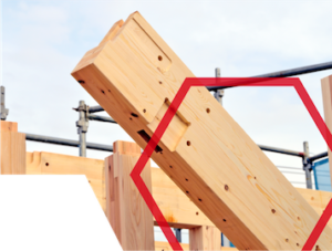 A close-up of interlocking wooden beams at a construction site, outlined with a red hexagonal shape.