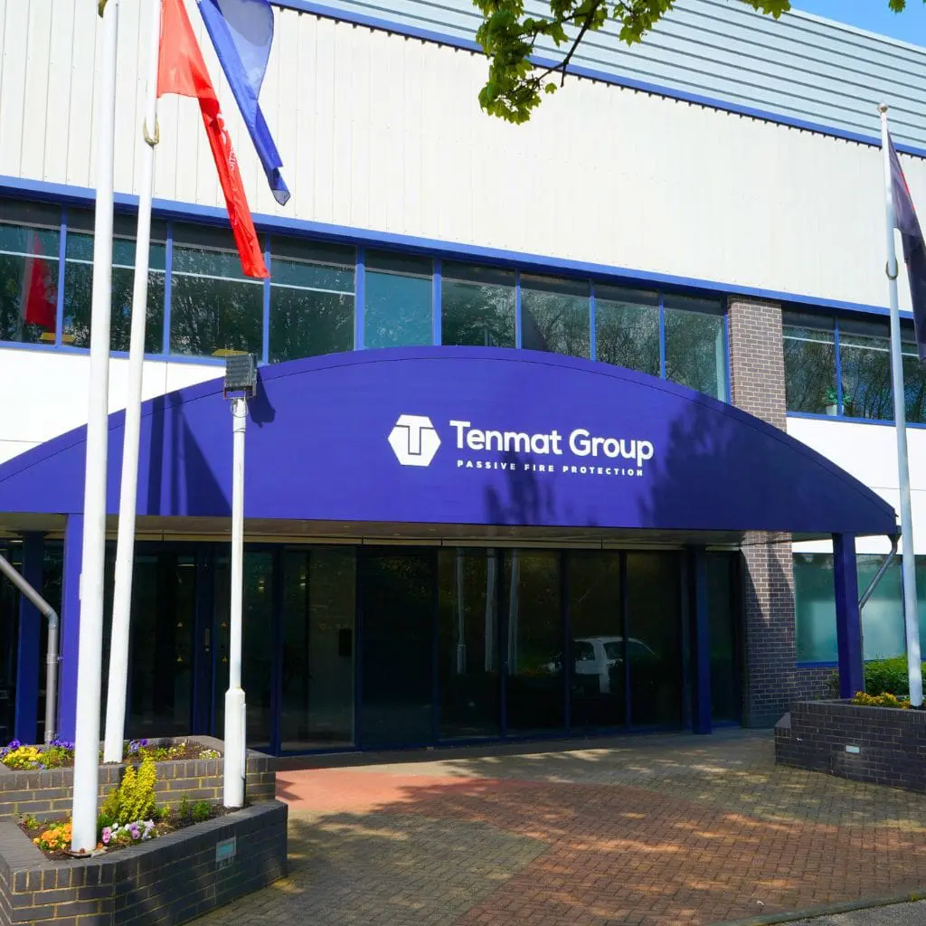 Tenmat Group entrance with blue awning and flagpoles outside.