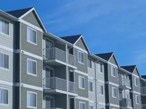A modern apartment building with balconies under a clear blue sky.