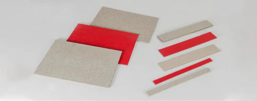 Rectangular and narrow strips of red and beige sheet material, commonly used in passive fire protection, are arranged on a white background.