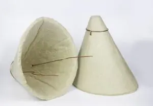 Two beige, conical hats with wire frames, resembling recessed light insulation covers, are displayed—one upright and one lying on its side—against a white background.