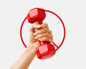 A hand gripping a red dumbbell with a red prohibition symbol in the background.