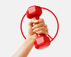 A hand gripping a red dumbbell with a red prohibition sign in the background.