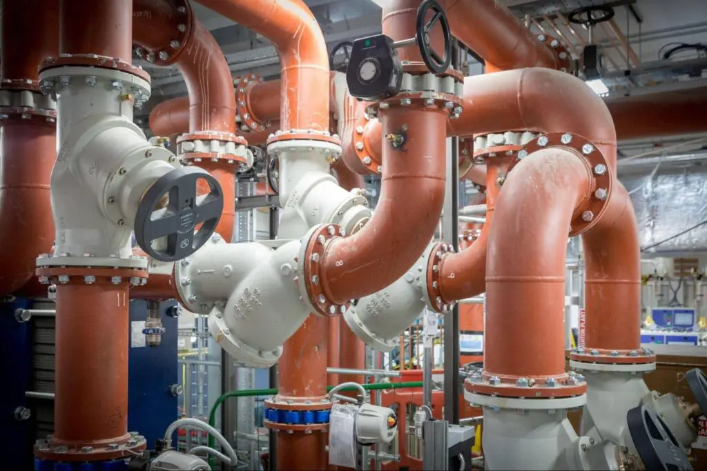 Red and white pipes with valves in an industrial mechanical room.