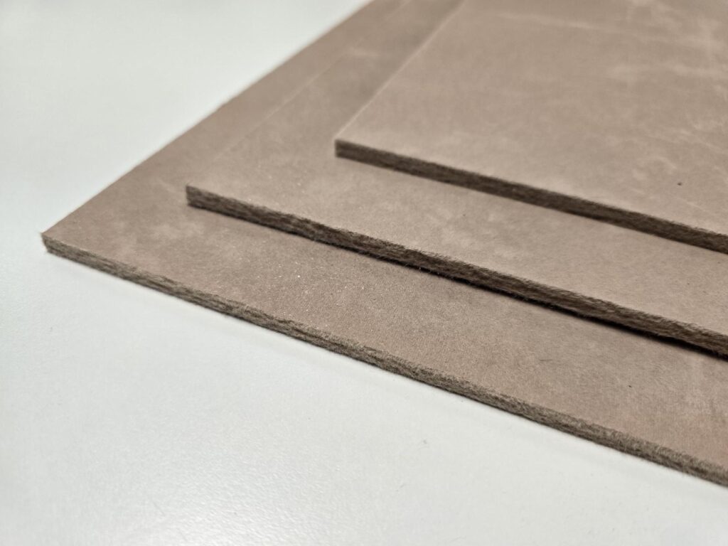 Three brown cardboard sheets stacked on a white surface.